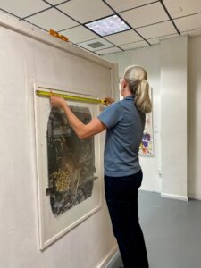 The National Gallery’s Meegan Ebanks installing Simon Tatum’s artwork at the Norman Centre Bridgetown, Barbados.